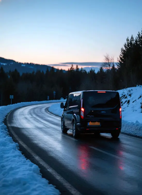 Coche circulando por carretera de montaña con nieve en los márgenes. Transporte seguro en invierno.