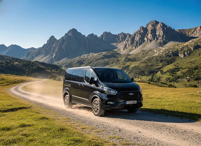 Vehículo 4x4 circulando por pista de tierra en alta montaña con vistas panorámicas del Valle de Arán.