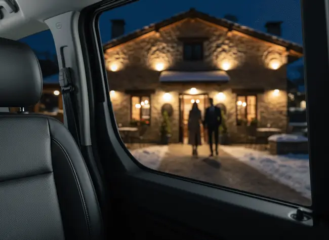 Vista desde el interior de un taxi de lujo hacia un restaurante de piedra iluminado en Arties de noche.